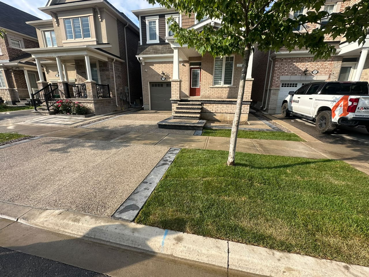 Exposed aggregate driveway, walkway and curb running across a full house frontage with fresh sod