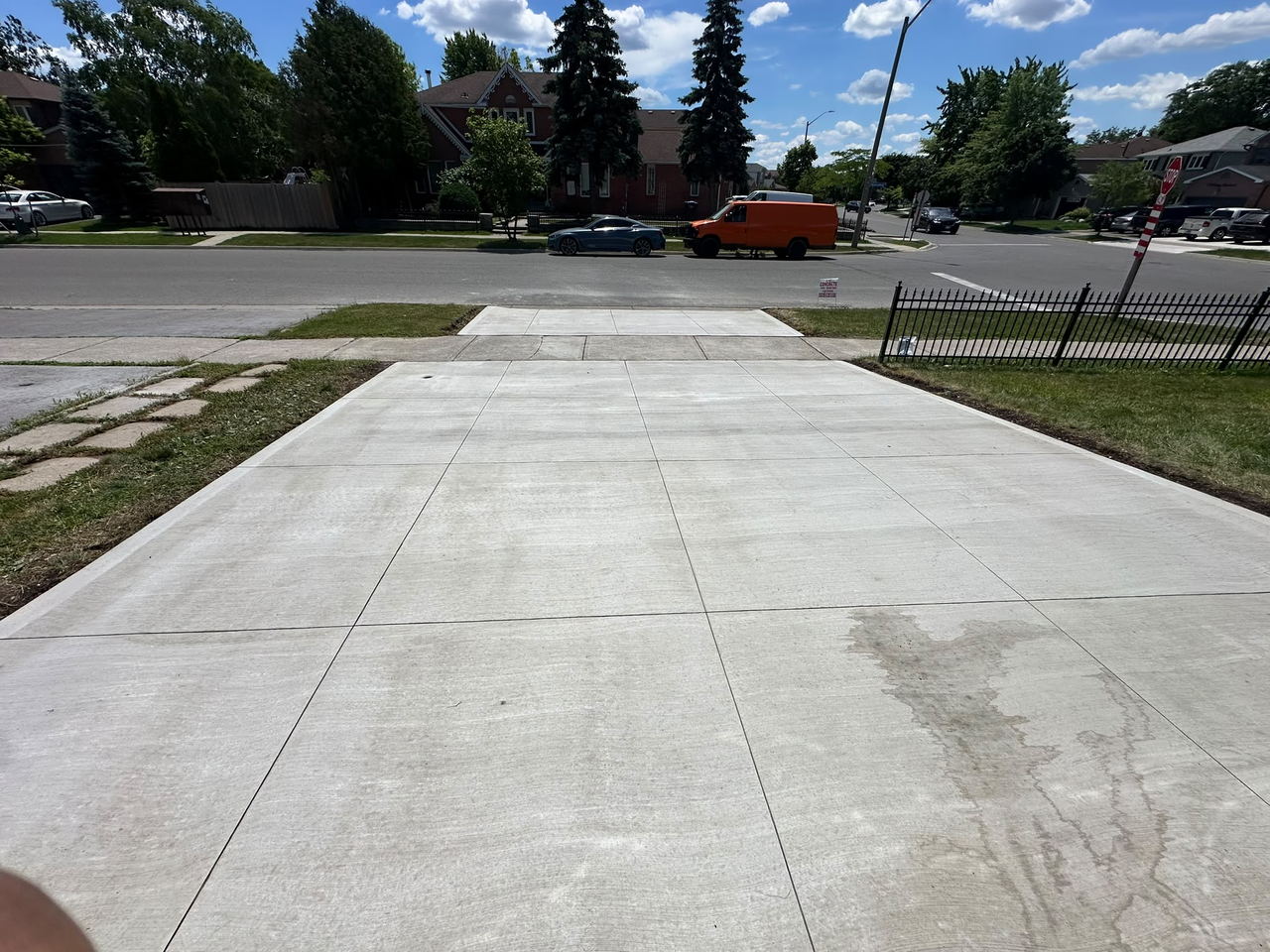 Wide broom-finish concrete driveway running from the garage out to the street