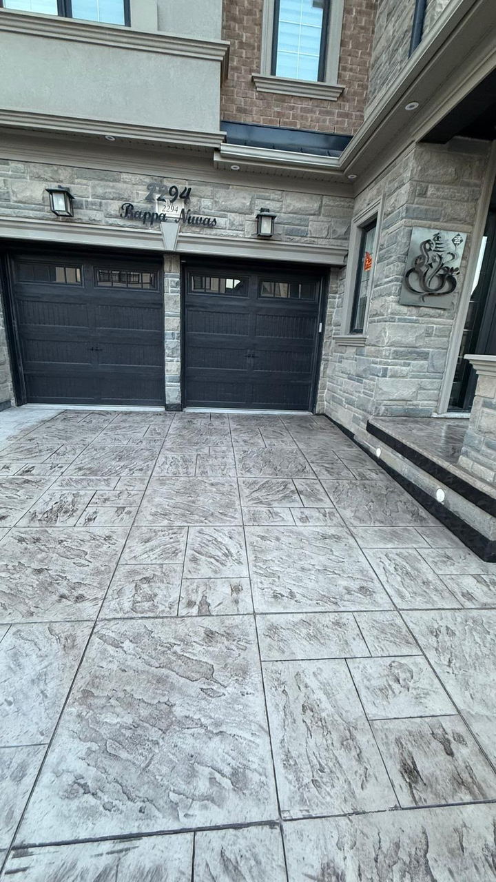Stamped ashlar apron and walkway in front of a dark double garage