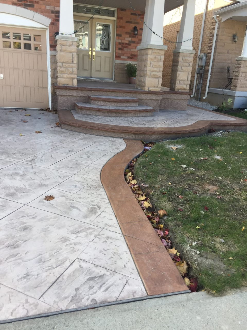 Stamped concrete driveway with a rust-toned border curving toward the front steps
