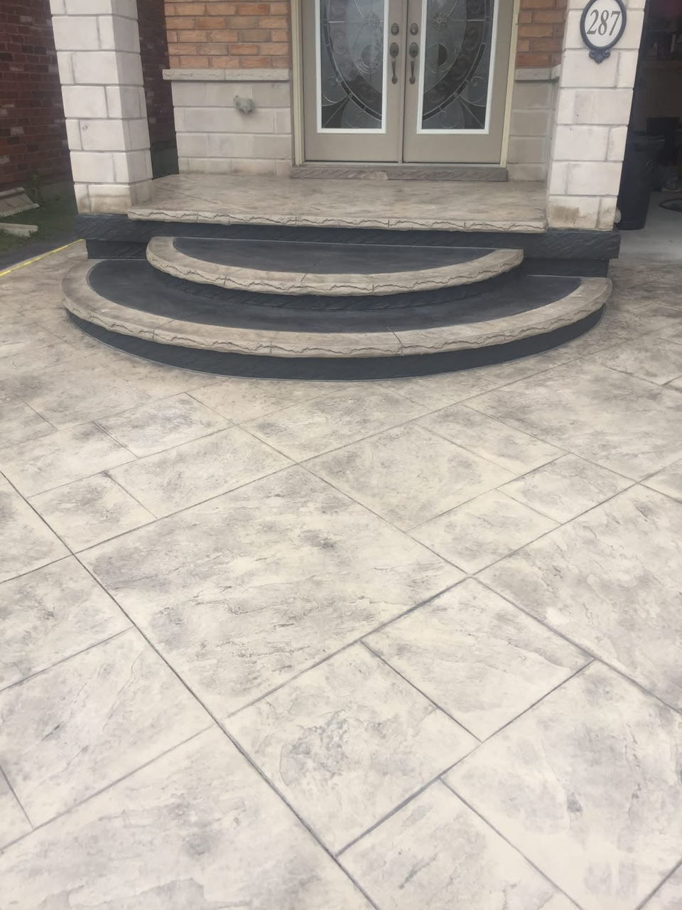 Stamped landing with rounded, dark-edged steps at a double front door