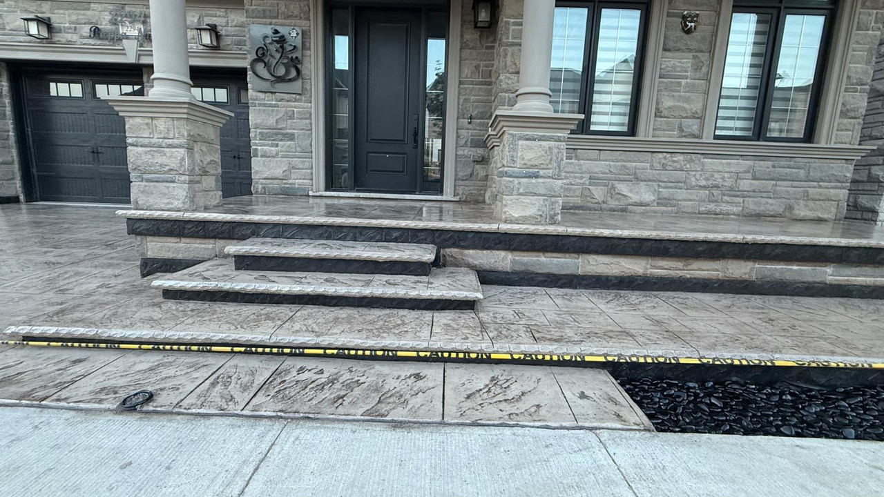 Stamped concrete porch, steps and walkway at a large stone-fronted home