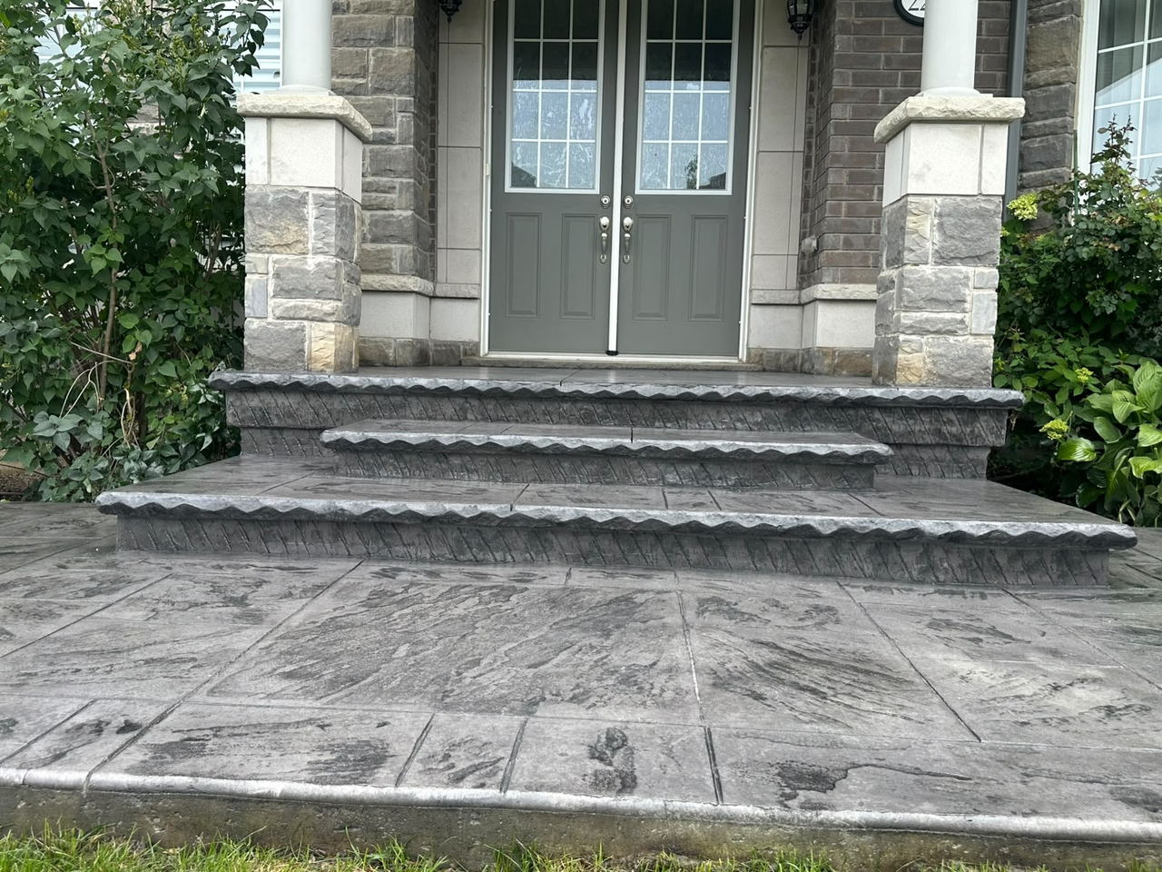 Grey stamped concrete porch and steps with rock-face edging at a double-door entrance