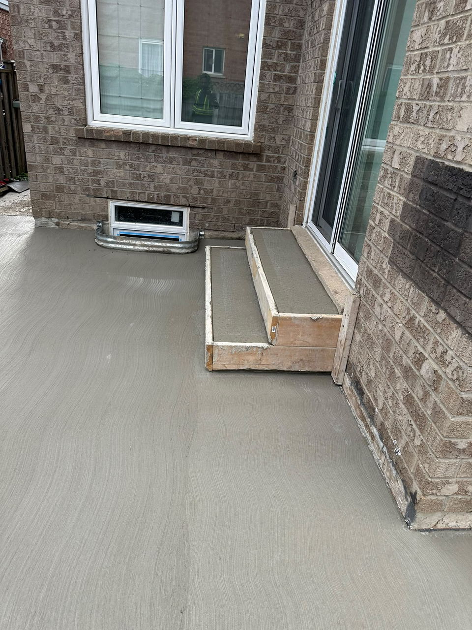 Smooth-finished concrete slab freshly poured beside a house, still in its forms