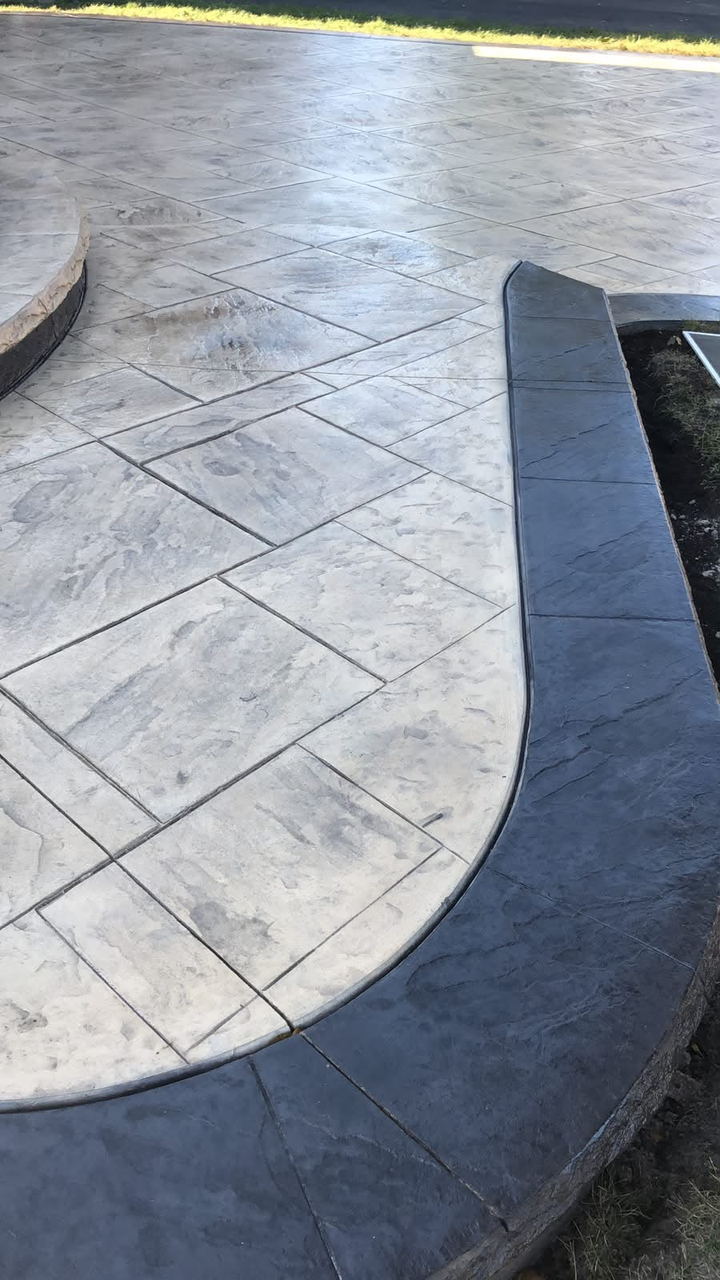 Close detail of a stamped ashlar surface meeting a curved charcoal border