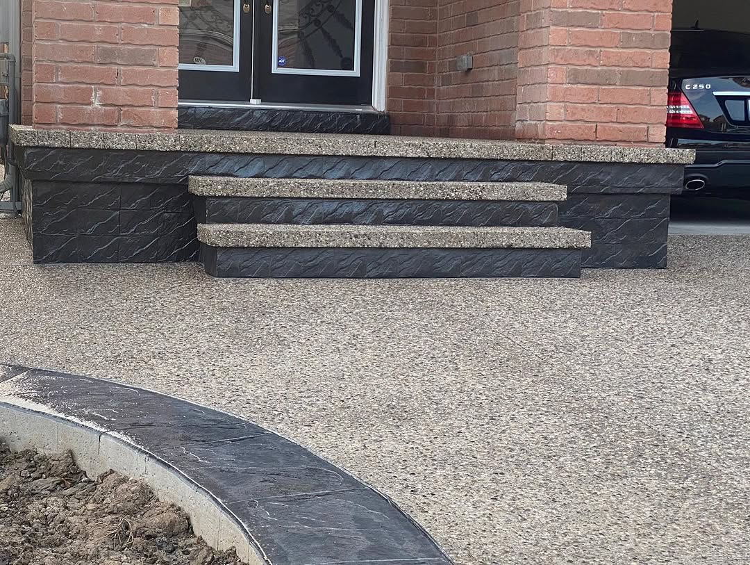 Exposed aggregate steps with dark stamped risers and a finished driveway in Elmira