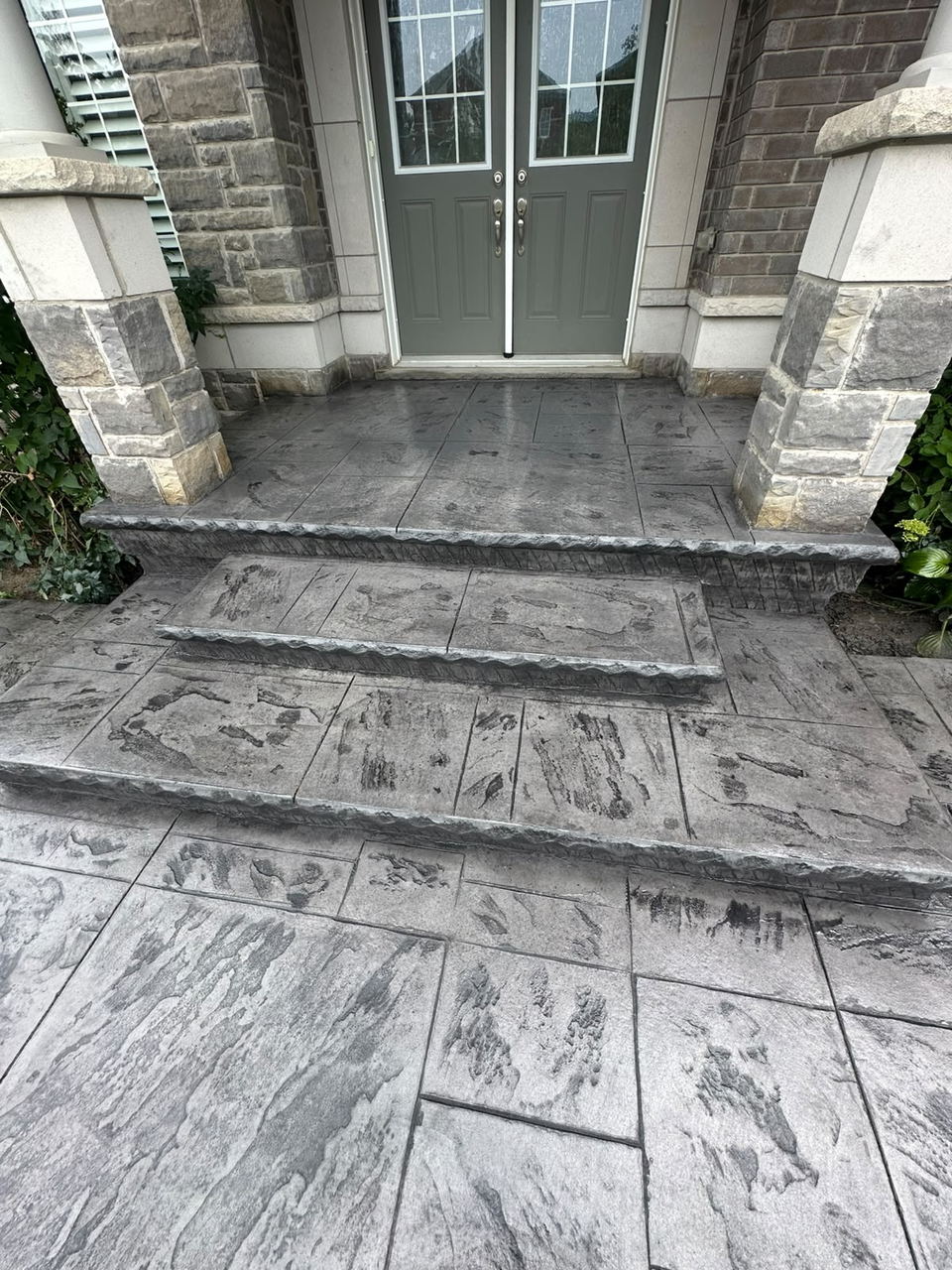 Close view of grey stamped concrete front steps and landing in a slate pattern