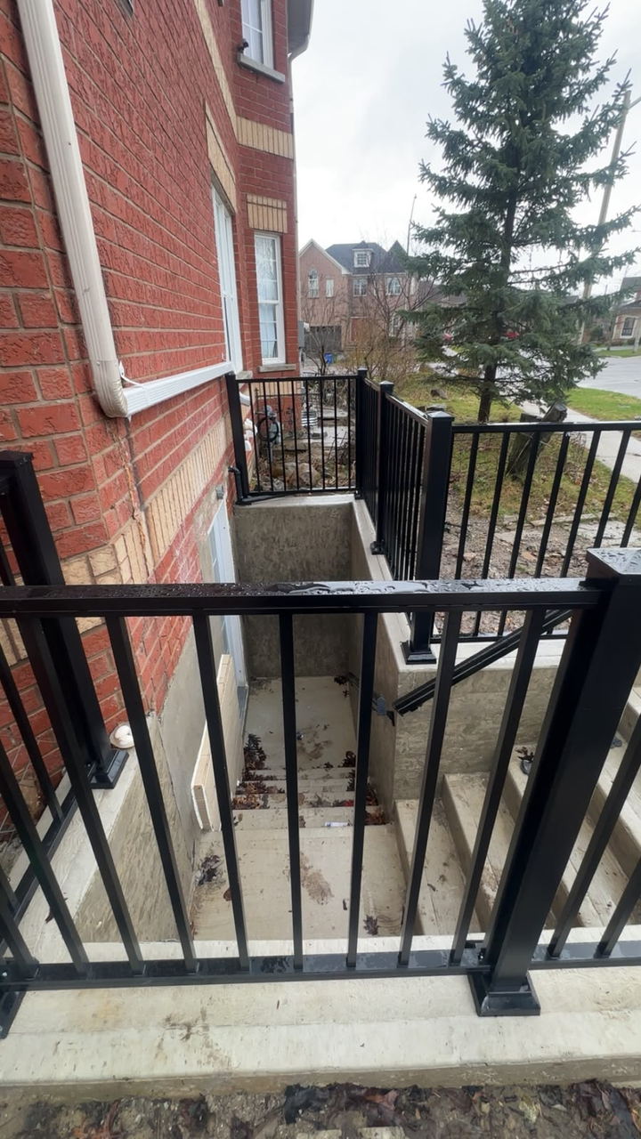 Poured concrete basement walkout stairs and retaining walls with black aluminium railings