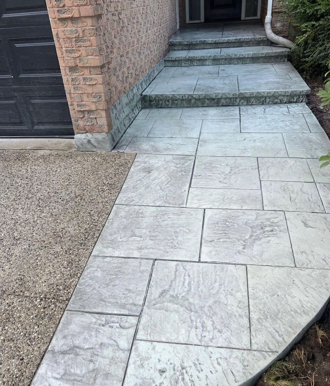 Stamped concrete walkway meeting an exposed aggregate driveway at the garage steps