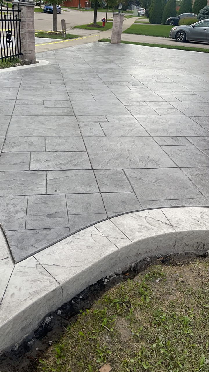 Stamped ashlar walkway with a curved charcoal border edging a garden bed